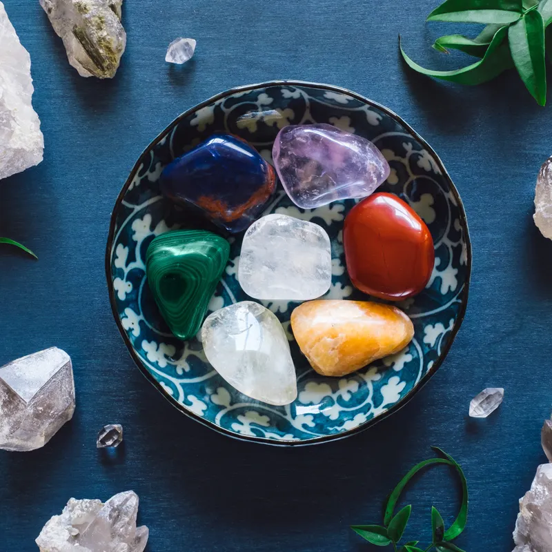 A bowl of gems is seen on a blue table.